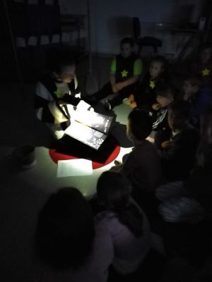 Zdjęcie z zajęć - dzieci słuchające bajki czytanej po ciemku